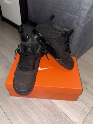 Svarta Air Jordan 4 sneakers - Säljer ett par helsvarta Air Jordan 4 sneakers med klassisk mesh och läderdetaljer. Skorna har högt skaft, ikonisk Jumpman-logga på plösen och robust sula med synlig Air-enhet. Perfekta för dig som gillar streetstyle och vill ha något stilrent. Pris kan diskutera