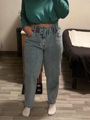 Ljusblå mom jeans  - Säljer ett par ljusblå mom jeans med trendig papperspåse-midja och hög midja. Jeansen har raka ben och klassisk femficksdesign. Perfekta för en avslappnad och cool stil. Materialet är denim i bomull.