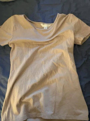 Beige t-shirt från H&M - En basic beige t-shirt från H&M med rund halsringning och korta ärmar. Tillverkad i mjuk bomull, perfekt för en enkel och clean look. Passar till allt och är superenkel att styla med andra plagg.