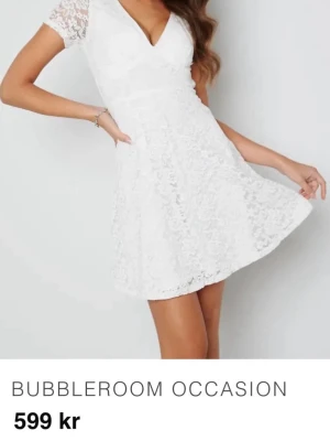 Studentklänning från Bubbleroom - Superfin vit klänning från Bubbleroom med v-ringning och korta ärmar i spets.    Den här dragkedja på sidan som gör den lätt att ta på och ger fin passform. Haft klänning vid ett tillfälle och den är som i nyskick. Köpt för 599kr