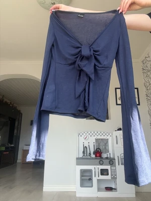 Marinblå långärmad topp - Trendig mörkblå långärmad topp med djup v-ringning och snygg knytning framtill. Tunt och mjukt material som ger en skön känsla. Perfekt att styla med jeans eller kjol för en cool look💗Kolla in min profil för fler fina och trendiga plagg!