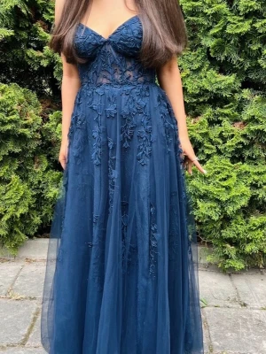 Marinblå långklänning med spetsdetaljer - Säljer en marinblå balklänning,använd 1 gång, skulle säga att den är i bra skick bara att den har ett litet hål där nere men som inte syns. Jag är 1,57cm och den passar mig perfekt i längden