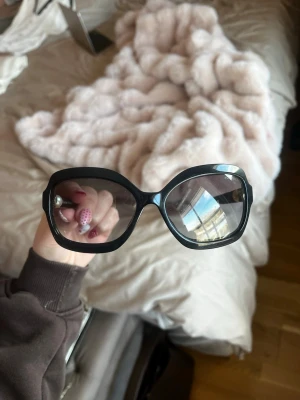 Svarta solglasögon från Chanel - Stilrena svarta solglasögon från Chanel med ikoniska pärldetaljer på sidorna. Perfekta för att lyfta vilken outfit som helst.