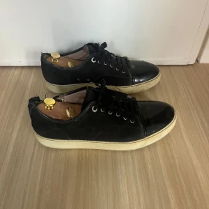 Lanvin skor  - Säljer mina gamla lanvin skor i storlek 44-45. Färgen är svart och cap toen är glansig. Skicket är bra förutom skadan på höger fot. Då de är mina gamla har hunden tråkigt nog bitit på de. Sulan är lite använd men inga andra skador.