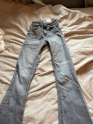 Grå bootcut jeans från only  - Säljer ett par gråa bootcut jeans från only Jeansen har klassisk femficksmodell, normalhög midja och utsvängda ben. Materialet är mjukt denim med stretch för extra komfort. 