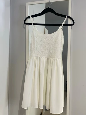 Vit spetsklänning - Söt vit klänning med spets och tunna axelband. Kjolen är lätt utsvängd och faller fint, perfekt för sommarens alla tillfällen. Passar även bra för skolavslutningar. 🥰Klänningen är i storlek xs och i mycket bra skick, inga defekter. 