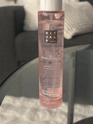 Rituals The Ritual of Sakura parfym - Fräsch och blommig hår- och kroppsmist från Rituals, The Ritual of Sakura. Flaskan är cylinderformad i genomskinligt rosa plast med vitt lock. Doften har inslag av körsbärsblom och ger en lätt, elegant känsla.