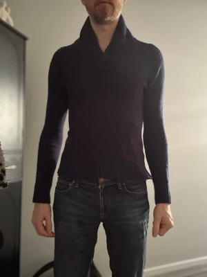 Mörkblå stickad tröja cheap Monday  - Mörkblå stickad tröja med hög, bred krage och långa ärmar. Tröjan har en smal slim passform och ribbstickade muddar. Liten cheap Monday logga sitter i nacken. Perfekt för kalla dagar.