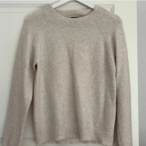 Beige stickad tröja från Vero Moda - Mysig beige stickad tröja från Vero Moda med rund halsringning och ribbade muddar vid ärmslut och nederkant. Perfekt för lager på lager och enkel att matcha med jeans eller kjol. Tillverkad i mjukt material som känns skönt mot huden.