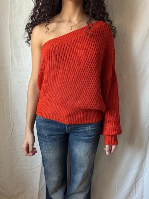 Röd stickad off shoulder tröja - Cool röd stickad tröja med off shoulder-design / oneshoulder och en lång ärm. Tröjan har bred ribbstickning och en avslappnad passform som ger en trendig look. Perfekt för dig som vill sticka ut och gillar att kombinera stickat med jeans. Pris kan diskuteras!🥰
