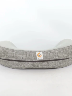 Grå amningskudde från Ergobaby - Säljer en ergonomisk amningskudde från Ergobaby i grått tyg med mjuk, ljusgrå plysch på ovansidan. Kudden har en böjd form som ger bra stöd vid amning och ett diskret mönster på tyget. Perfekt för bekväm matning.