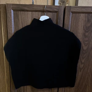 Svart polotröja utan ärmar - En stilren svart polotröja med hög krage och ärmlös design. Tröjan har en enkel och clean look, perfekt att matcha med olika outfits. Verkligen super fin på!