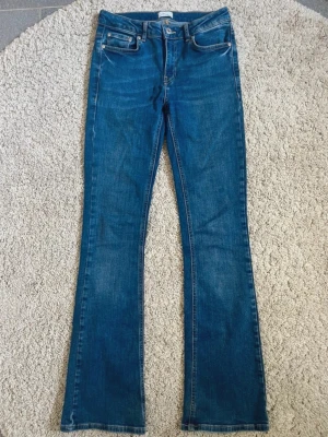 Blå bootcut jeans  - Snygga blå bootcut jeans med klassisk femficksdesign och normal midja. Endast använda en gång, som nya. Innerbenslängd: 77cm. Midjemått rakt över: 32cm💓