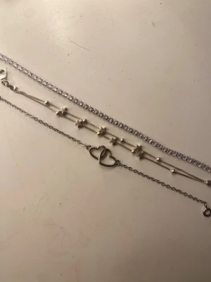 Silverfärgade armband - Säljer tre snygga armband i silverfärg. Ett har gnistrande stenar, ett har små stjärnor och pärlor, och det tredje har två sammanlänkade hjärtan. Perfekta för att mixa och matcha till olika outfits. 1 för 30kr, 2 för 50 och 3 för 65❣️