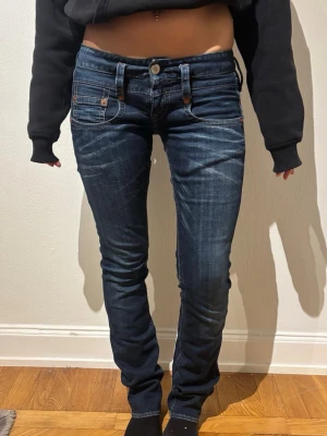 Mörkblåa skinny jeans från True Religion - Säljer ett par mörkblåa skinny jeans från Herrlicher med kontrastsömmar och klassiska fickor både fram och bak. Jeansen har låg midja, smal passform och är tillverkade i stretchigt denim för extra komfort. Perfekta för en trendig och avslappnad look.