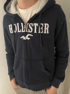 Mörkblå zip hoodie från hollister - 🌟Storlek S! 🌟Inga defekter!  🌟Priset kan såklart diskuteras✅  Obs! Det står storlek M men passar bättre som storlek S.  Modellen är 180 och väger 65.