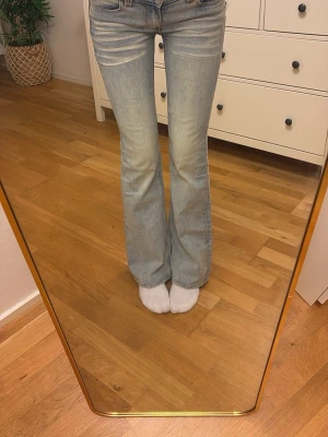 Ljusblå bootcut jeans Cheap Monday - Säljer ett par ljusblå bootcut jeans från Cheap Monday med cool grön logga där bak. Jeansen har klassisk femficksmodell, låg midja och lätt slitna detaljer. Perfekta för dig som gillar stockholms vibe och vill sticka ut lite extra. Säljer då de är för stora!!