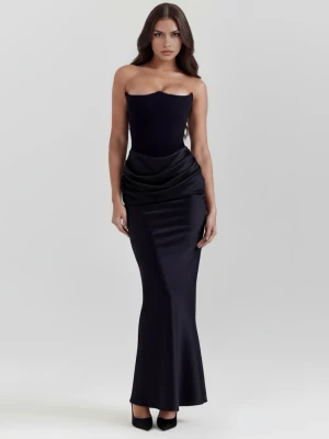 Svart axelbandslös långklänning - Elegant svart axelbandslös långklänning med draperad detalj över höfterna och figurnära passform. Klänningen har en slät, glansig yta och stängs med dragkedja i ryggen. Perfekt för dig som vill ha en stilren och sofistikerad look. Säljes pga för liten, helt oanvänd.