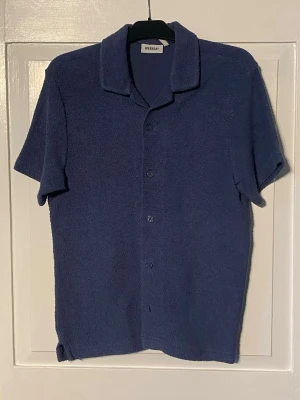 Weekday frottéskjorta  - Kortärmad skjorta i frotté från weekday. Denna i en lite grövre frotté vilket ger av en häftig unik struktur till plagget. Perfekt till sommaren. Sitter S. Säljer billigt då jag desperat behöver plats i garderoben 😅