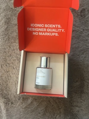 Fruity Honey parfym från Dossier - Fruity Honey parfym från Dossier i en stilren, genomskinlig glasflaska med silverfärgat lock. Doften har fruktiga och söta honungstoner. Flaskan har en minimalistisk etikett med tydlig text och modern design. Endast testad