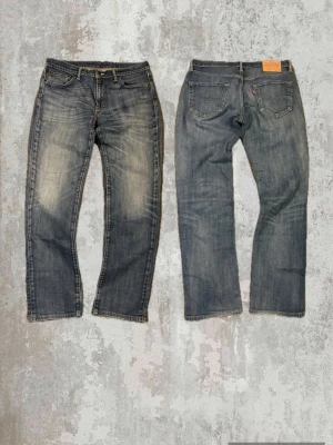 Levi's 511 blå sjuk tvätt - Säljer ett par klassiska Levi's 511 slim jeans i blå tvätt med slitningar och snyggt blekta partier. Jeansen har fem fickor, dragkedjegylf och den ikoniska läderlappen bak i midjan. Perfekta för en avslappnad och trendig look.