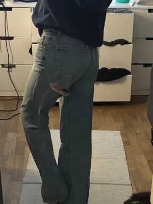 Blå low rises jeans med slitningar - Säljer ett par trendiga ljusblå  jeans med låg midja från Zara. Jeansen har raka ben och snygg slitning i bak