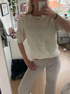 Vit stickad topp med puffärm - Söt vit stickad topp med korta puffärmar och rund hals. Toppen har en mjuk och lite lös passform, perfekt att styla med smycken för en trendig look. Enkel och stilren design som passar till mycket. Passar S super också 