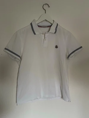 Moncler pike - Hej nu säljer vi denna otroligt fina autentiska moncler piké i en vit färg. Storlek på denna är S. Skick 9/10 inga skador eller defekter. För fler frågor eller funderingar är det bara att höra av sig. 