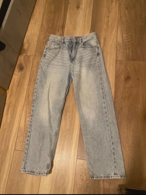 Ljusblå raka jeans - Säljer ett par ljusblå jeans med rak passform och klassisk femficksdesign. Jeansen har hög midja och är tillverkade i denim med en lätt tvättad look. Perfekta för en avslappnad och trendig stil.