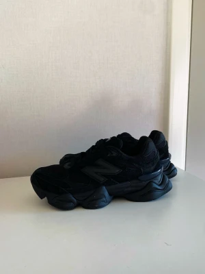 Svarta New Balance sneakers chunky - Säljer ett par helsvarta sneakers från New Balance med chunky sula och sportig design. Skorna har en blandning av mocka och meshmaterial, samt den klassiska N-loggan på sidan. Perfekta för dig som gillar streetwear och vill ha en modern look.