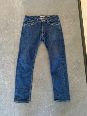 Mörkblå raka jeans - Säljer ett par klassiska mörkblå jeans med rak passform och fem fickor. Jeansen har normal midja och stängs med dragkedja och knapp. Perfekta till en avslappnad stil och passar till det mesta. Materialet är denim i bomull.