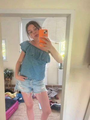 One shoulder jeans topp - Jeanstopp som är tänkt vara off sholder, men jag har använt den som one shoulder! Strl 140 vilket låter väldigt litet, men passar bra på mig som kan ha XS. Säljer för 75kr!
