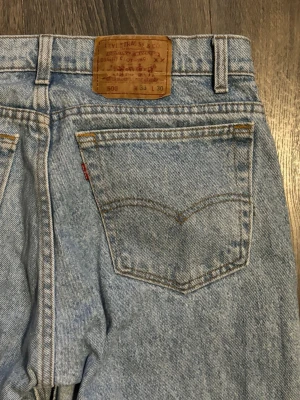 Levi's 505 jeans - Klassiska Levi's 505 jeans i ljusblå denim med rak passform och hög midja. Jeansen har fem fickor, gylf med dragkedja och den ikoniska läderlappen bak i midjan. Perfekta för en avslappnad och tidlös stil.