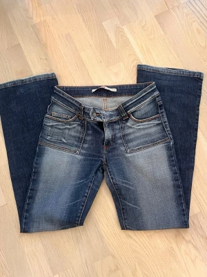 Blå lågmidjade  bootcut jeans från Only - Säljer ett par blå lågmidjade bootcut jeans från Only i storlek 38. Perfekta för dig som gillar retrostil och vill ha ett par jeans med lite vidare ben.