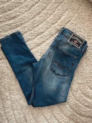 Replay Anbass jeans  - Snygga blåa replay Anbass jeans. Midja 43cm, längd 99cm. Längd storleken saknas, men jag skulle bedöma till L32 - emn utgå efter mått. Obs jeansen har en liten fläck baktill på låret. Samt vänstra framfickan är det ett hål i. JAG SKICKAR EJ FLER BILDER NÄR JAG BÄR JEANSEN! för bättre inblick i passformen rekommenderar jag att googla på modellnamnet. För storleksguide kolla måtten noggrant då jeansen alltid kan vara uppsydda heller krympta och jag ej tar emot returer :) 1,100