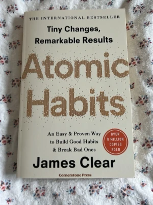 Atomic Habits av James Clear - Atomic Habits av James Clear är en internationell bästsäljare på engelska med vit och guldaktig framsida. Boken handlar om hur små förändringar kan ge stora resultat och innehåller tips för att bygga goda vanor och bryta dåliga. Perfekt för dig som vill utvecklas och bli mer produktiv.