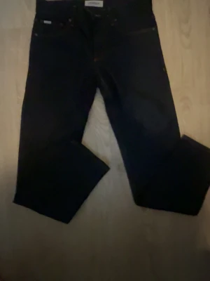 Mörkblå raka jeans - Säljer ett par mörkblå jeans med rak passform och klassisk femficksdesign. Jeansen har en enkel look utan slitningar och är tillverkade i ett kraftigare denimtyg. Perfekta för dig som gillar stilrena och tidlösa byxor. Helt nya, med ett nypris på 1499