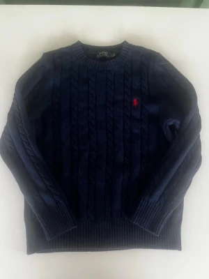 Ralph lauren kabelstickad tröja mörkblå marinblå  - Riktigt snygg ralph lauren kabelstickad tröja i mörkblå färg.fint skick inga fel storlek M kan ta mått vid behov. Endast 448kr ej hugget i sten kom gärna med frågor och prisförslag denna modell på tröja är lite stickig men inget som känns mycket har även mycket mer liknande i min profil alla storlekar kolla gärna stor rabatt vid köp av flera 😁✌️