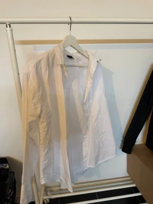 Vit klassisk skjorta från Gina Tricot - Säljer en vit klassisk skjorta från Gina Tricot. Skjortan har lång ärm, krage och knappar framtill. Perfekt basplagg i garderoben och lätt att styla till olika looks. Tillverkad i mjuk bomull för en bekväm känsla.