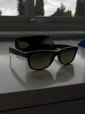 Ray-Ban New Wayfarer - Hej, säljer dessa supersnygga RayBan glasögon i modell New Wayfarer. Glasögonen är i superfint skick utan märkbara defekter förutom lite damm. De är även polariserade vilket gör de extremt sköna i solen. Ingår gör ett original RayBan fodral. 