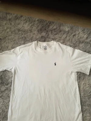 Vit t-shirt från Ralph Lauren - Du kan köpa Shortsen och T-shirten för 500. Kolla min profil. Klassisk vit t-shirt från Ralph Lauren med den ikoniska broderade loggan på bröstet. T-shirten har rund hals och korta ärmar, tillverkad i mjuk bomull för en skön känsla. Perfekt basplagg till garderoben.