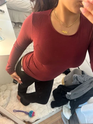Mörkröd långärmad topp - Säljer en mörkröd långärmad topp med rund halsringning. Toppen har en slim passform och är tillverkad i ett mjukt och stretchigt material, perfekt för en enkel och stilren look.