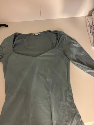 Ljusgrön långärmad topp från Amisu - Ljusgrön långärmad topp från Amisu med fyrkantig ringning. Toppens material känns mjukt och stretchigt, perfekt att styla med jeans eller kjol. Enkel och stilren design som passar till många olika looks.