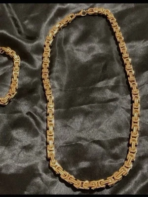 Kungslänk Set 8 mm – Halsband + Armband Guldpläterat - Tyngre, tätare och mer exklusivt än många standardmodeller. En premiumkedja med snygg lyster och rejäl känsla som syns direkt.  • Halsband: ca 60 cm / ca 150 g • Armband: ca 60 g • Bredd: 8 mm  Material: Rostfritt stål med flerskiktad 18K guldplätering och slitstark PVD-beläggning.  ✓ Tung premiumkänsla ✓ Blank och exklusiv finish ✓ Vattentåligt material ✓ Färg som håller länge ✓ Hypoallergent  Perfekt för dig som vill ha en kraftigare kedja Trendigast nu under sommaren 
