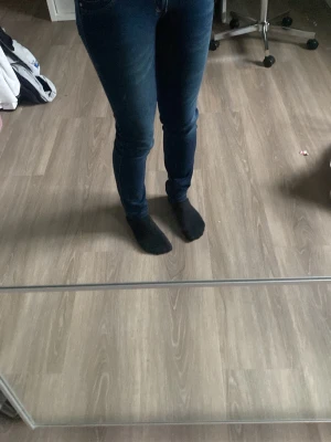 Mörkblå skinny jeans - Säljer ett par mörkblå skinny jeans med klassisk femficksdesign och smal passform hela vägen ner. Jeansen har normal midja och är tillverkade i stretchigt denimtyg för en bekväm känsla. Perfekta för dig som gillar en tight och stilren look.