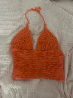 Coral virkad halterneck linnetopp - Handgjord coral virkad linnetopp med halterneck och knyt i nacken. Toppen har trekantsformade kupor och öppen rygg med snörning. Perfekt för sommaren och ger en cool boho-vibe.