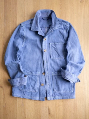 Blå Chore Jacket, size M - Ljusblå overshirt i bomull med tre stora utanpåfickor och träknappar framtill. Jackan har klassisk krage och raka ärmar som enkelt kan vikas upp för en mer avslappnad stil. Perfekt för lager på lager och enkel att matcha med olika outfits.