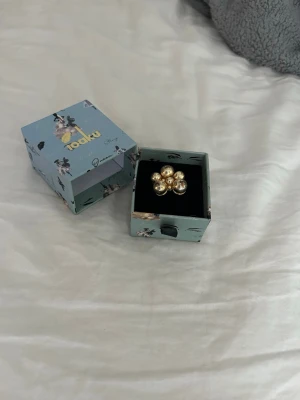 Guldfärgad blomring från Ioaku - Säljer en unik guldfärgad justerbar ring från Ioaku med blomformad design. Tyvärr har ringen börjat rosta lite trots att den inte är använd (hoppas det syns i bilderna)