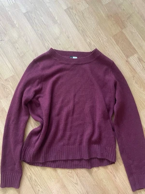 Vinröd stickad tröja med rund hals - Mysig vinröd stickad tröja med rund halsringning och långa ärmar. Tröjan har ribbade muddar vid ärmslut och nederkant samt en något lös passform. Perfekt för lager på lager och enkel att matcha med jeans eller kjol.❤️