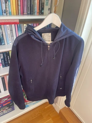 Boggi Milano cardigan /ziptröja – Mörkblå – Storlek S - Säljer en stilren hoodie med dragkedja från Boggi Milano. Mörkblå färg med snygga detaljer på huvan och praktiska fickor med dragkedja. Passar lika bra till vardags som till en mer uppklädd outfit.  ✅ Storlek M ✅ Dragkedja hela vägen ✅ Fickor med dragkedja ✅ Bekväm och stilren design ✅ Bra skick  Vid frågor eller intresse är det bara att skicka ett meddelande!